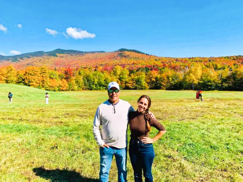 The author's family posing at the wide landscape in Stowe with fall foliage in the background