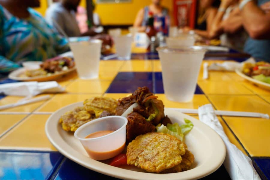 A meal on a plate with a dip and a glass of drink on its side