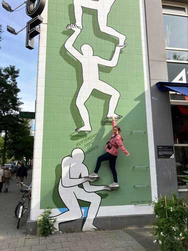 Meg O’Connor smiling for a photo with a street art in Rotterdam, Netherlands