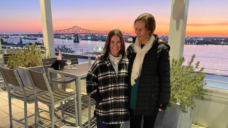 The author Meg O'Connor and a woman smiling for a photo at the rooftop restaurant Tsunami at sunset