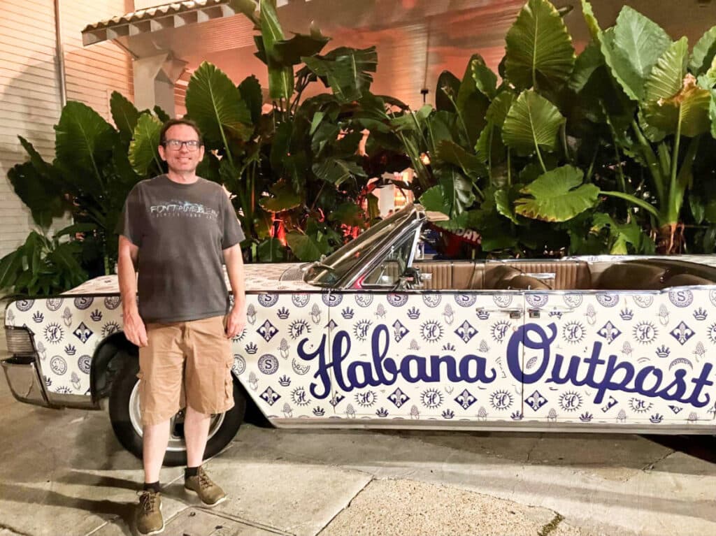 The author Meg O'connor's partner, posing near a vintage car with Habana Outpost text