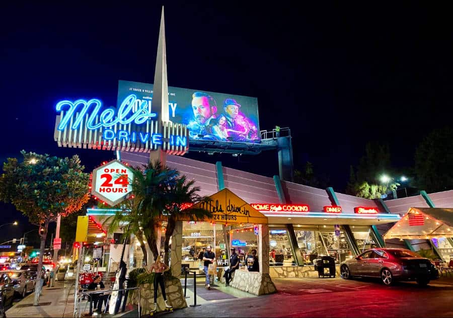Exterior view of Mel’s Drive-In with neon signs and billboard nearby