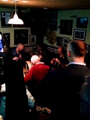 View of the men drinking alcohol and playing musical instruments in a dimmed room