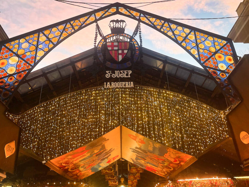View of the illuminated holiday lights on the facade of Mercado de La Boqueria during Christmas season at sunset