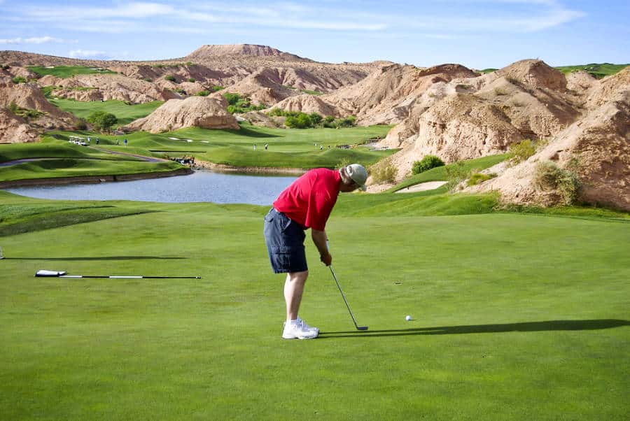 A man in a red shirt putting on the golf course