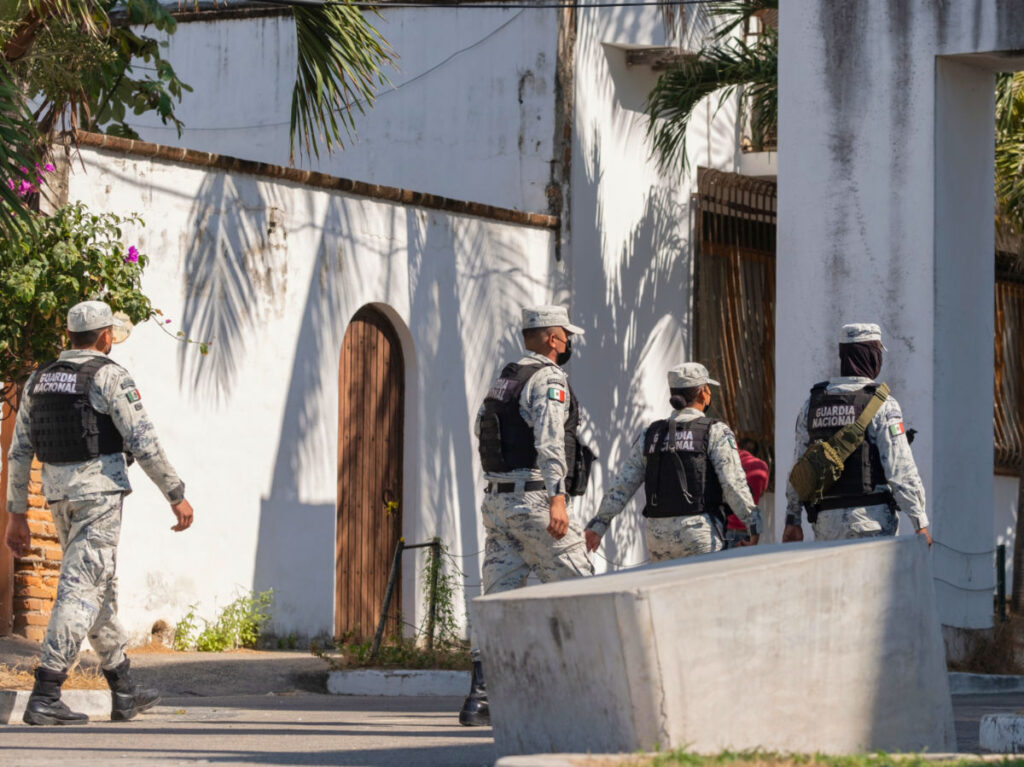 Group of Mexican National Guard officers in camouflage uniform patrolling the local city streets
