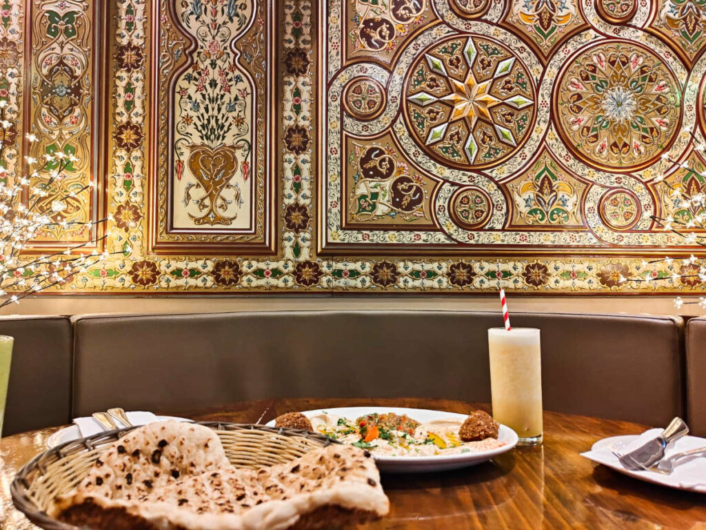View of the beautiful wall decor and the Mezza starter and Pineapple smoothie on the table at Shaam Nights