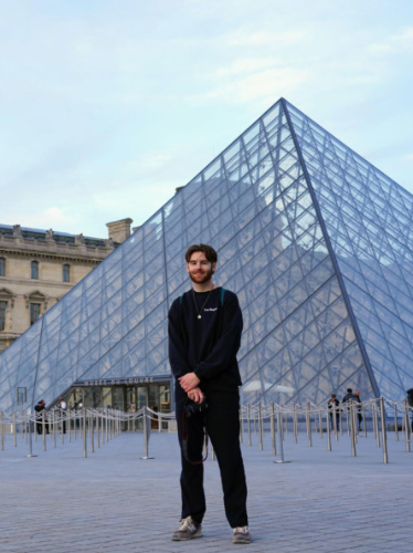 Michael posing for a photo in front of the Louvre pyramid