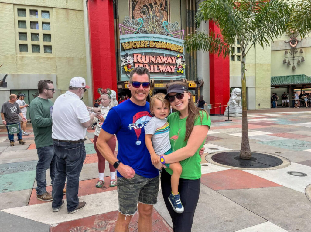 The author, Katie Neufeld with her husband and son in front of Mickey & Minnie’s Runaway Railway