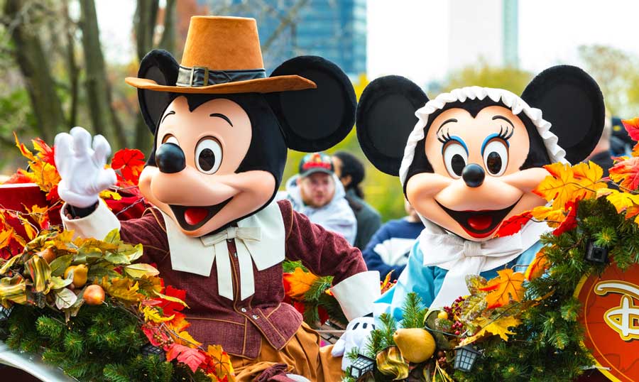 Mickey and Minnie Mouse waving their hands during a parade in Disneyland