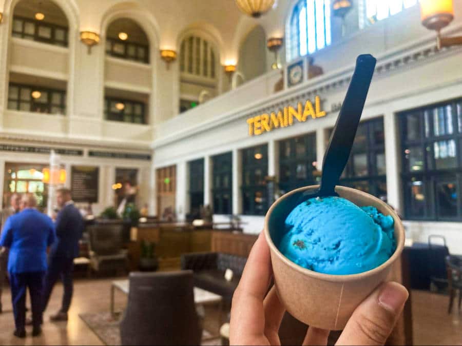 A hand holding a cup of blue ice cream from Milkbox Ice Creamery in Union Station