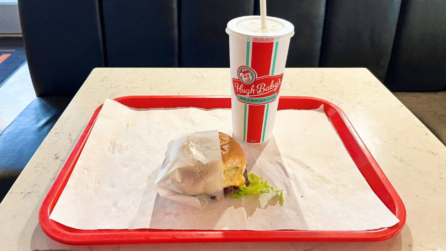 A red tray with a cup of milkshake and a burger from Hugh Baby’s