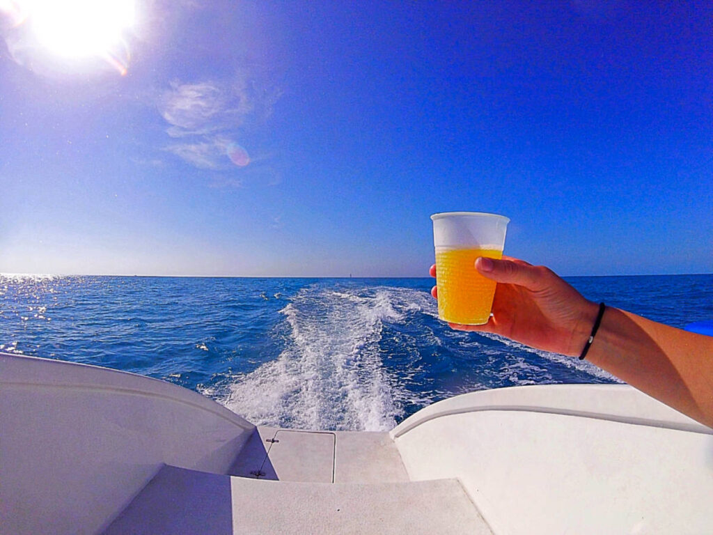 A hand holding a cup of mimosa on the boat