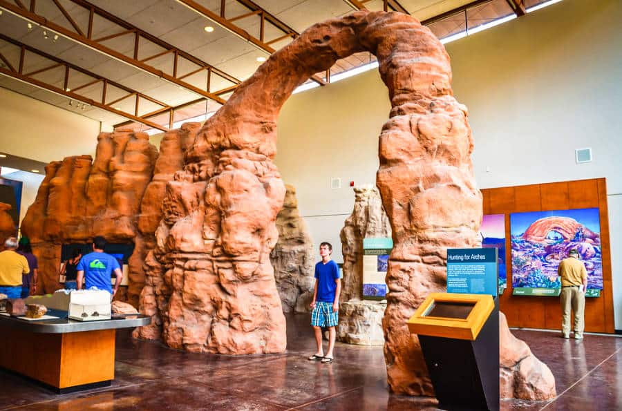 A man standing under the replica of a sandstone arch in the Moab Museum