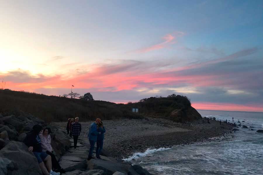 People relaxing at the shoreline of Montauk Point during sunset