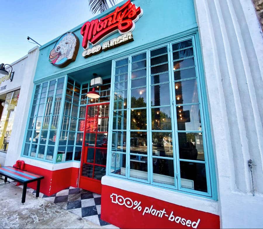 A vibrant light blue and red retro-inspired exterior of Monty’s Good Burger