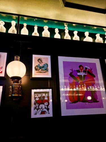 A dimly-lit lamp on the wall with the framed paintings inside Noble Rot