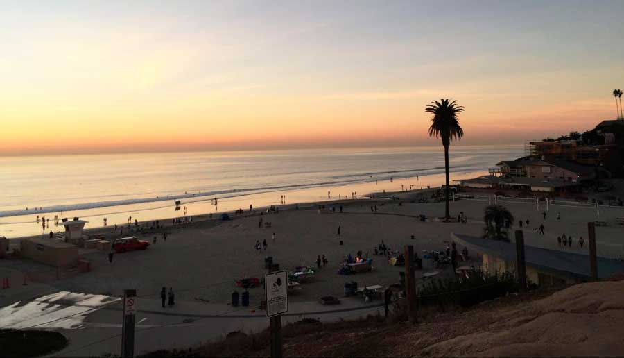 View of people enjoying their day in Moonlight Beach during sunset