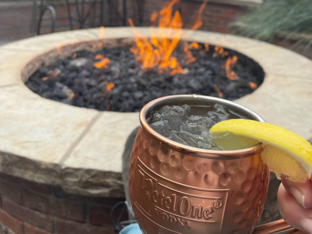 A cup of Moscow Mule with lemon and the fire in the background