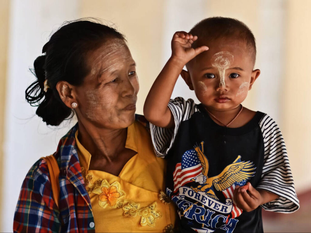 A woman holding a child with a painted face