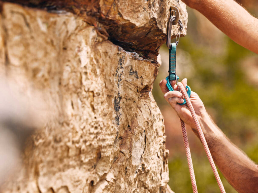 A hand holding the carabiner while mountain climbing