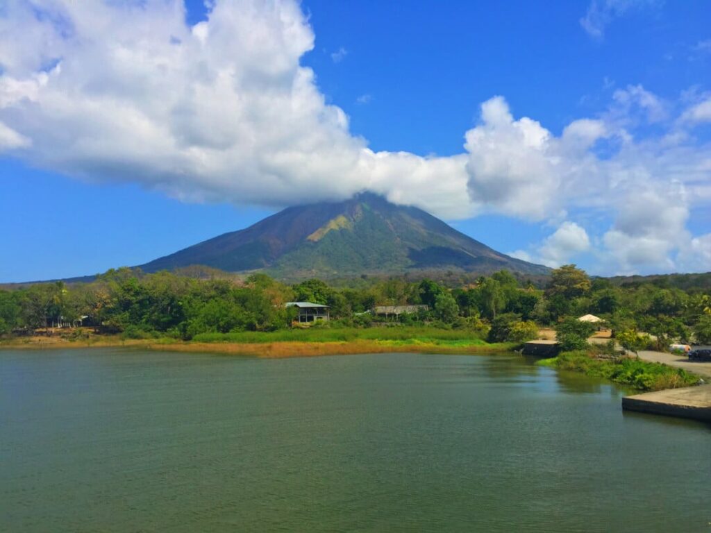 Blue sky over a mountain surrounded by a lake and greenery