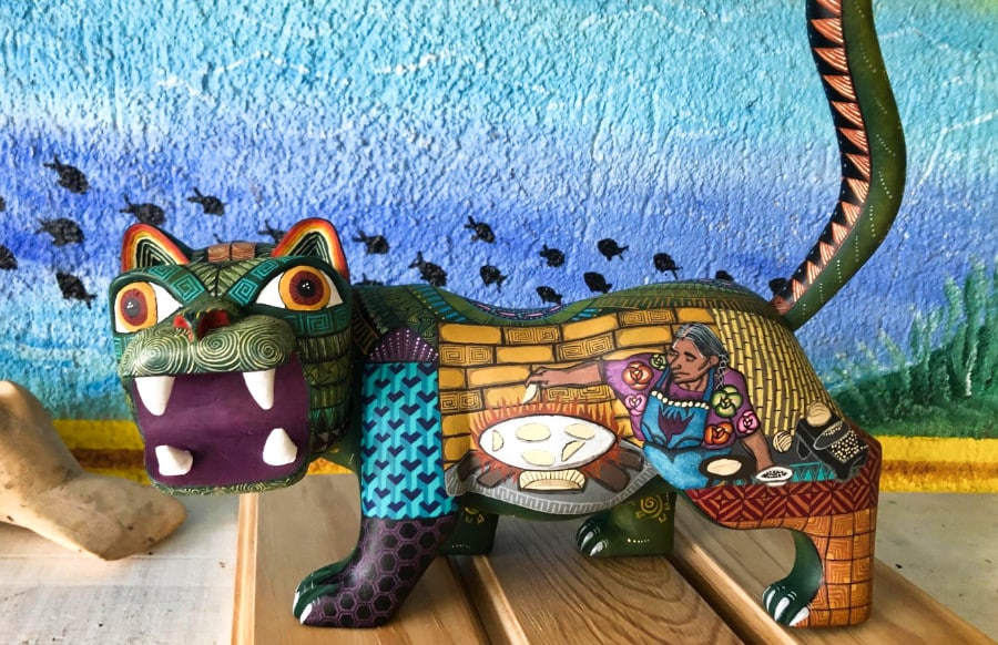 A traditional Oaxacan wood art piece with a colorful painted design