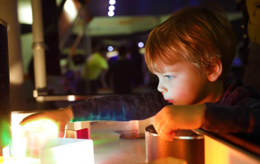 View of a little boy observing a light in a museum