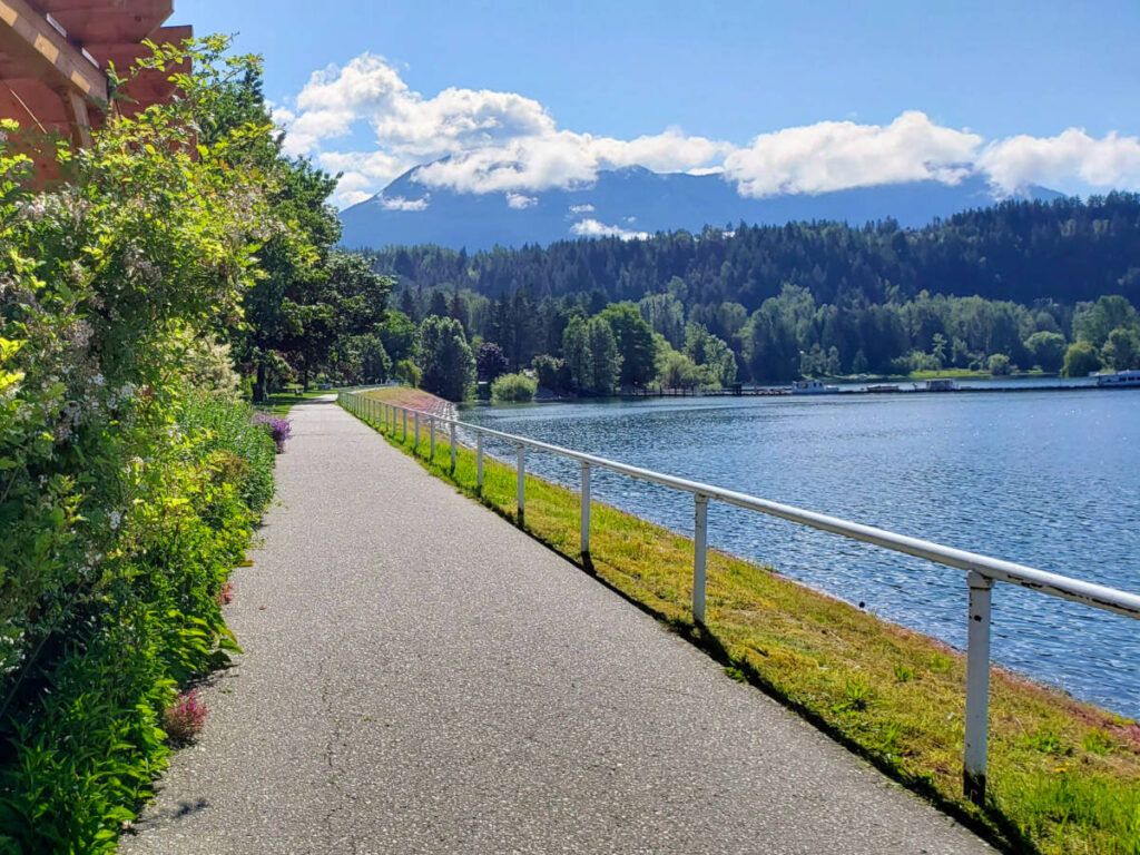 View of sidewalk with lake on the right in Nakusp