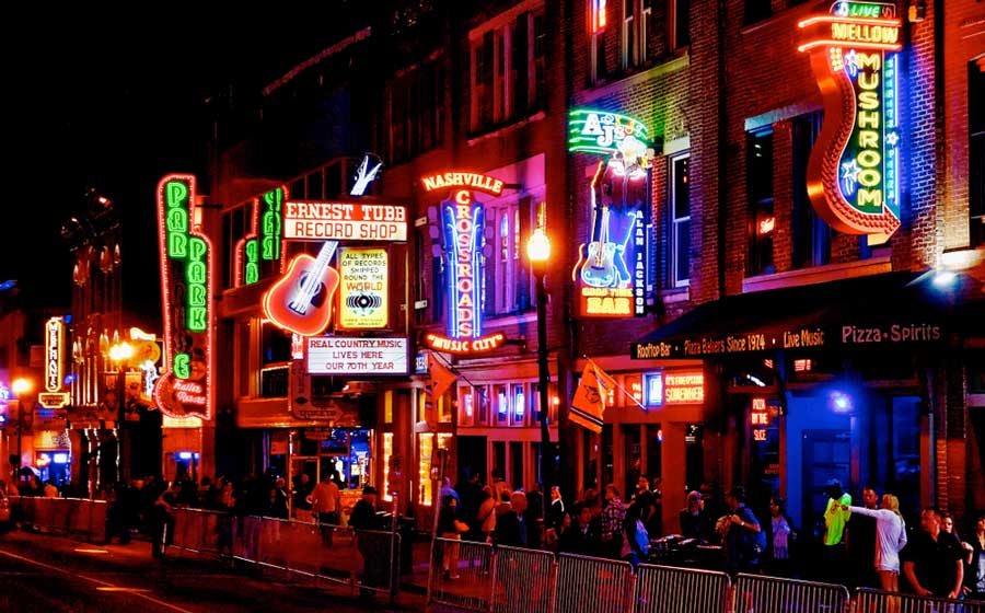 View of people and illuminated signs in Broadway at night in Nashville