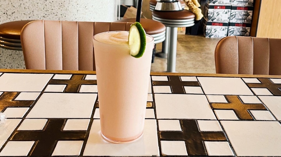 A smoothie with a slice of cucumber on the rim of the glass