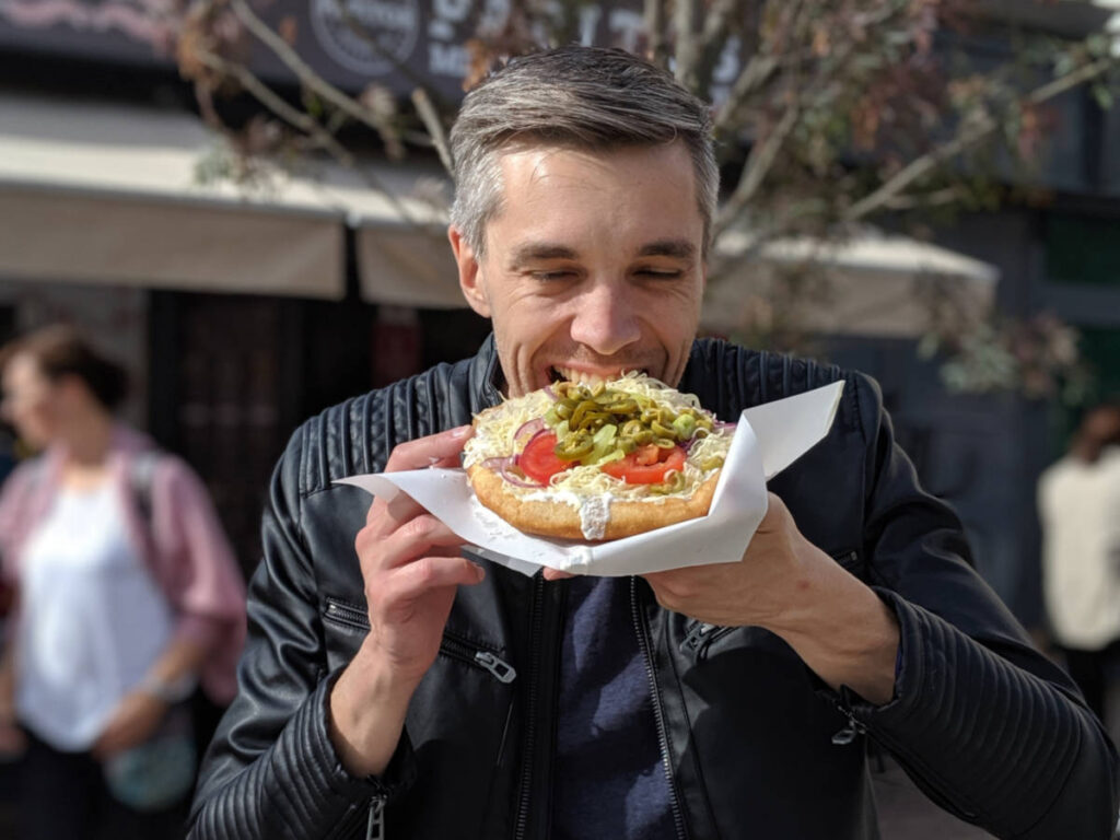 Travel Lemming Founder Nate Hake eating lángos in the middle of the street