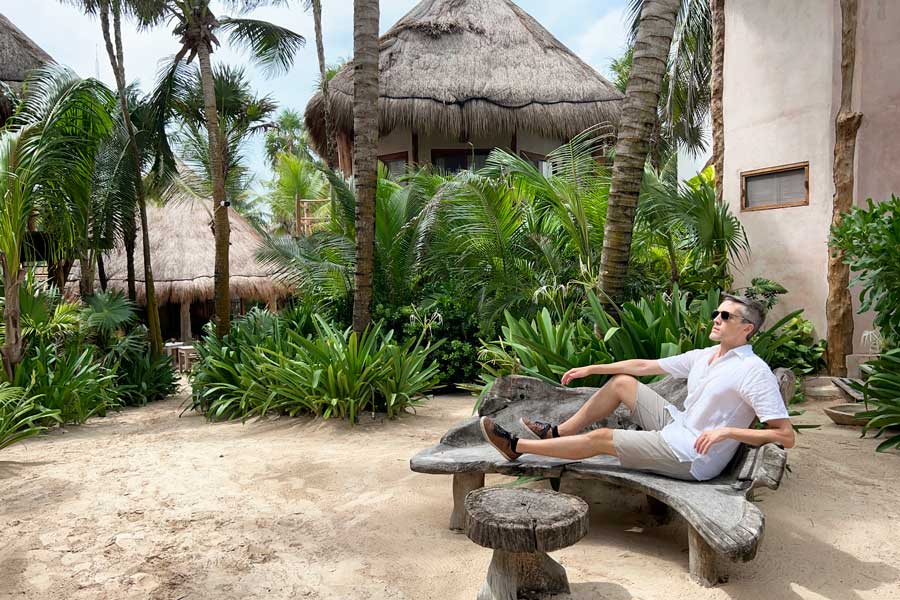 Nate posing for a photo while sitting on a chair in Encantada Tulum