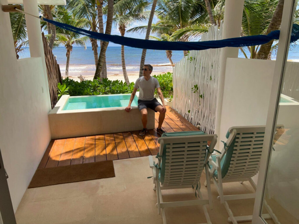 Travel Lemming founder Nate sitting near a mini pool on a sunny day at Cabañas Tulum