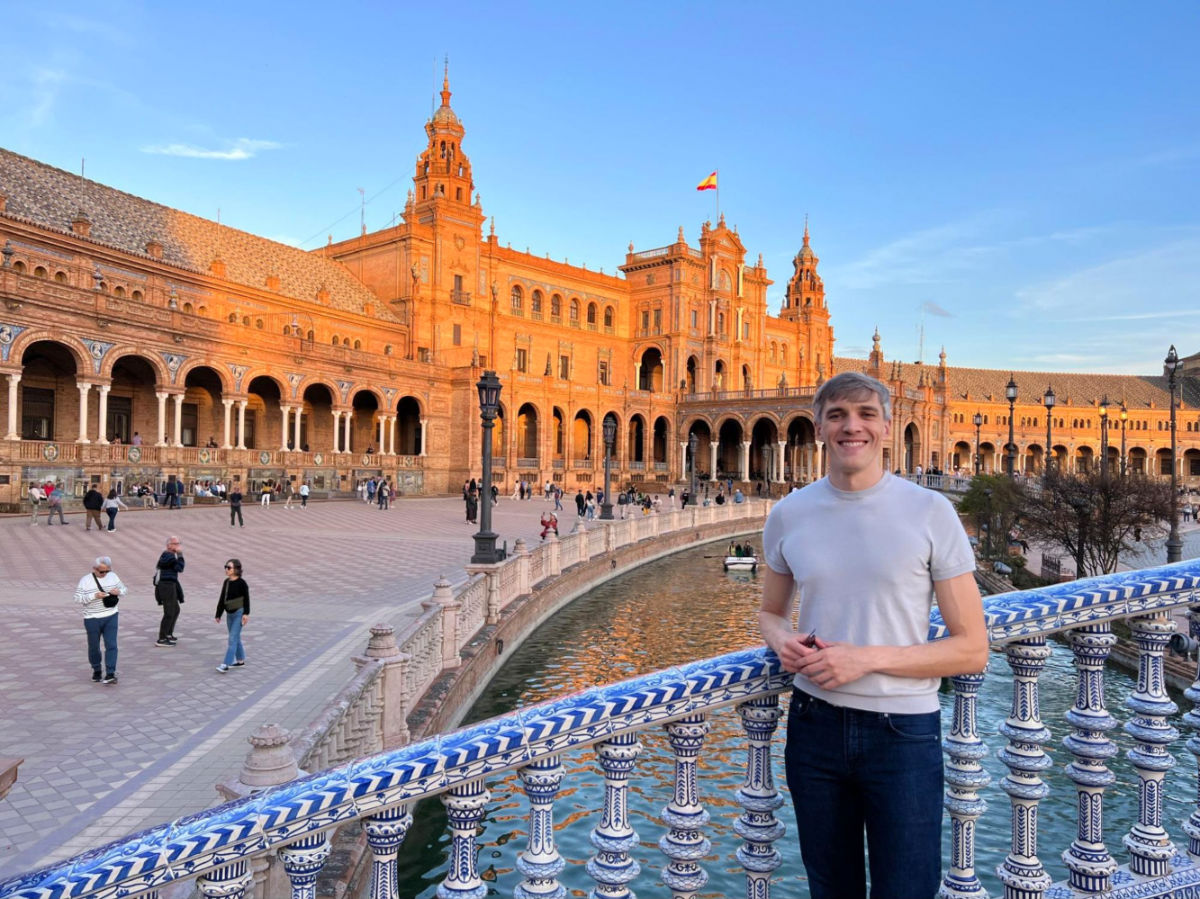 Travel Lemming founder Nate standing on a bridge with the Plaza de España in the background in Seville