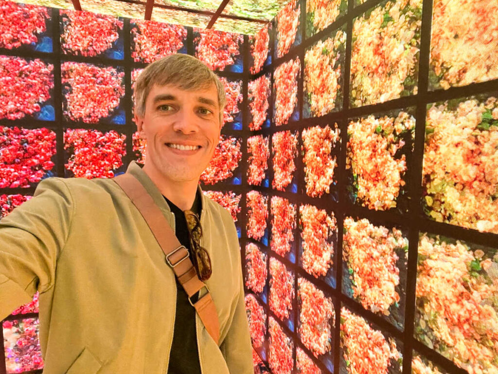 Travel Lemming Founder Nate Hake, smiling for a photo inside the vibrant digital art room