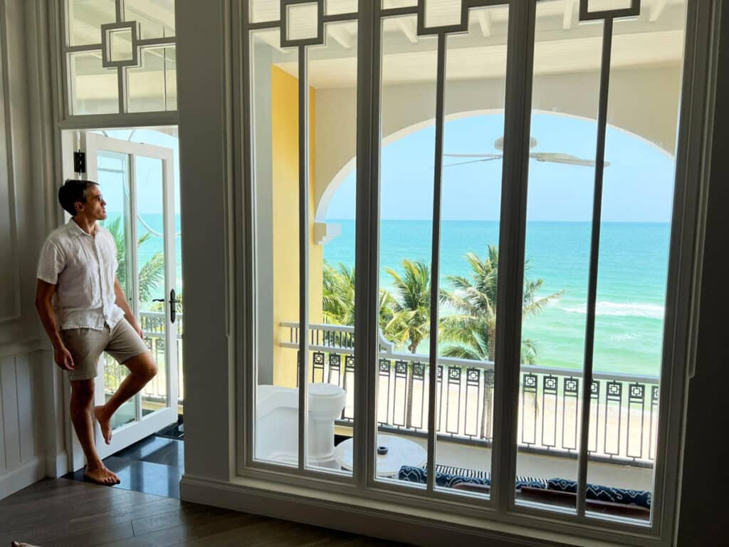 Nate admiring the view while standing on their room's door frame in JW Marriott Phu Quoc Emerald Bay Resort