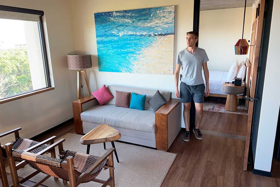 Nate posing for a photo on a living room area in a hotel room in Aloft Tulum