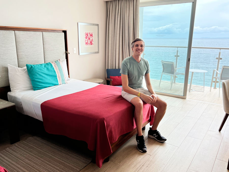 Nate sitting on a bed in a room un Grand Park Royal in Puerto Vallarta