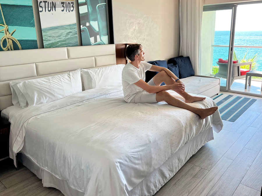 Nate sitting on a bed in Hilton Riviera Resort bedroom