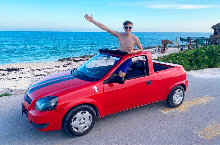 The author posing for a photo while on the rental car and a beach in Cozumel on his background