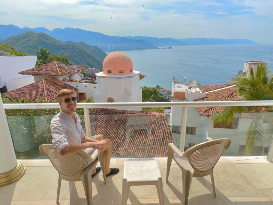 Nate sitting on a chair in a balcony with the view from Mondavi Wellness Resort and Spa