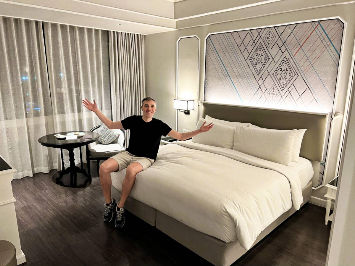 Travel Lemming founder Nate Hake sitting on the bed of Courtyard Phuket Town