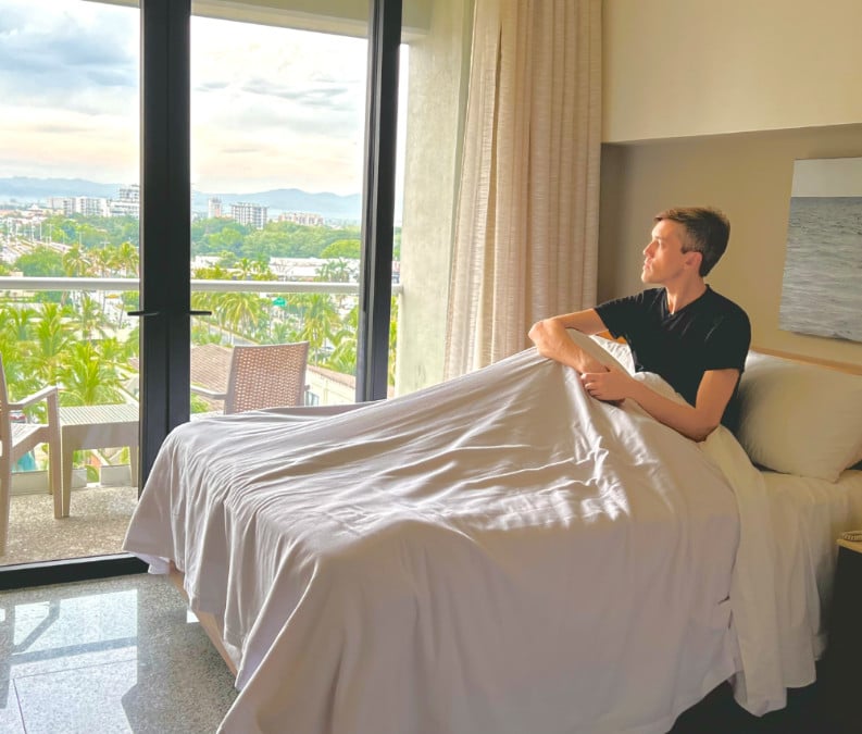 Nate sitting on a bed in Hotel Mio Vallarta