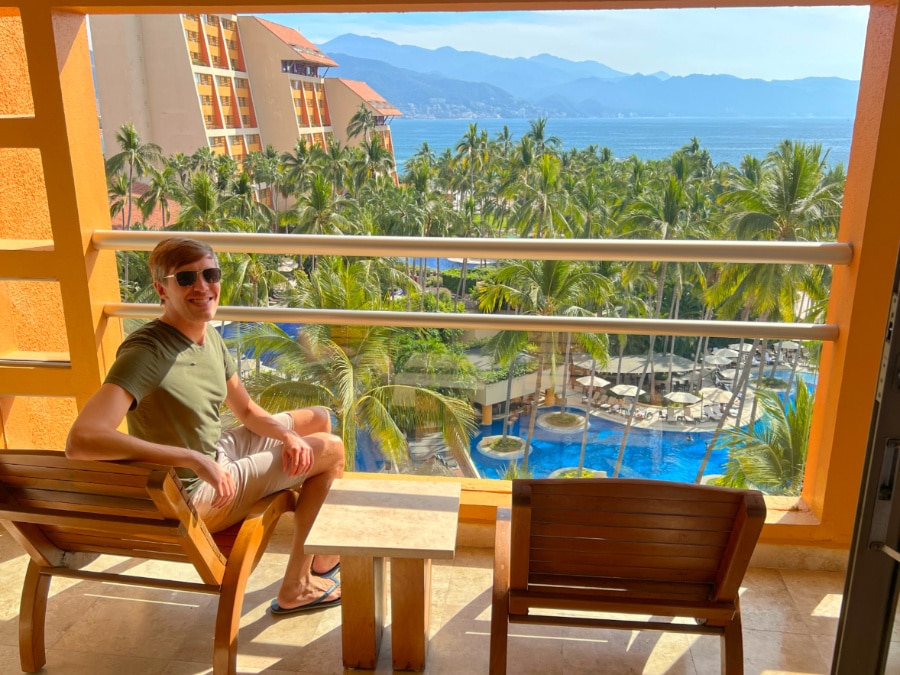 Nate sitting on a chair in the balcony with the view from the pool