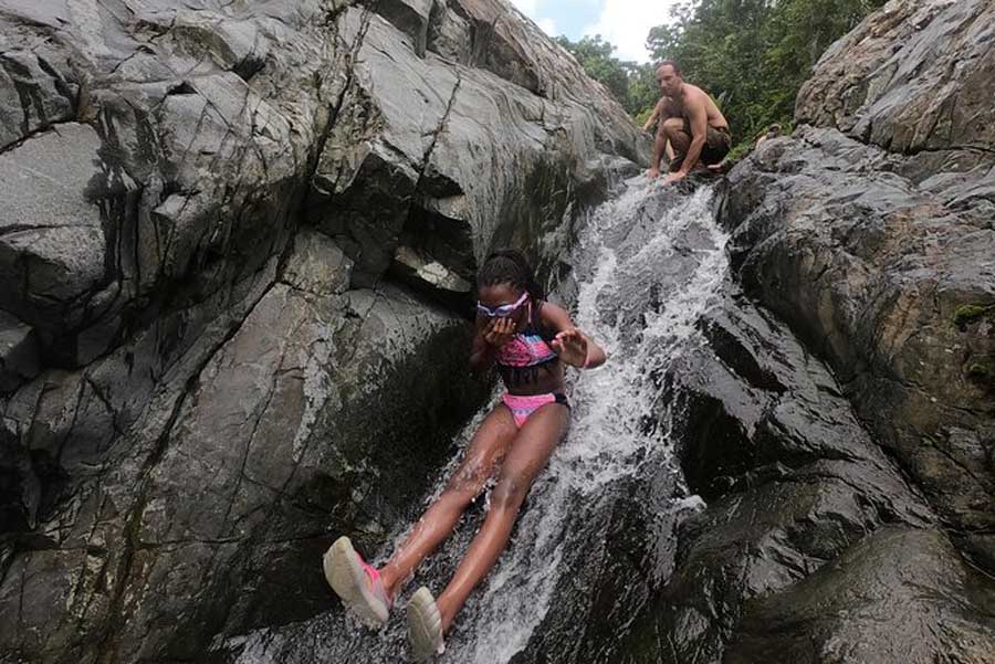 A girl sliding on the natural waterslide in El Yunque Rainforest