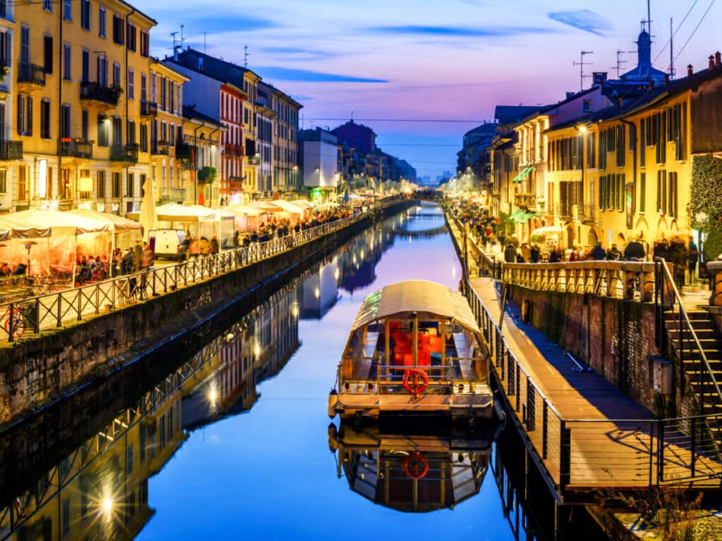 View of the illuminated Naviglo Grande canal with buy shops around at night