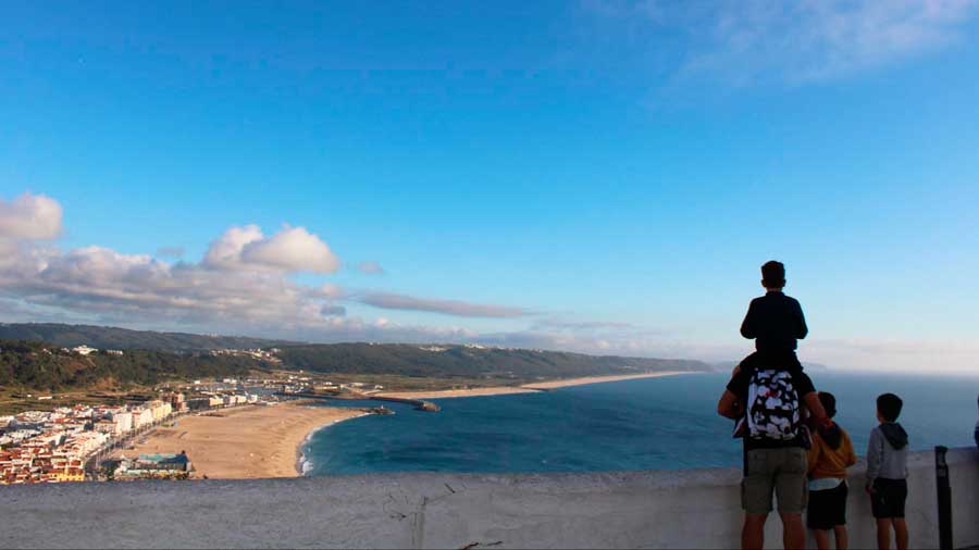 A father with his kids admiring the view of Nazare