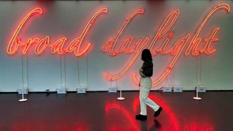 The author Lea Rose Allbaugh passing by the illuminated neon sign at the Museum of Contemporary Art Chicago (MCA Chicago)