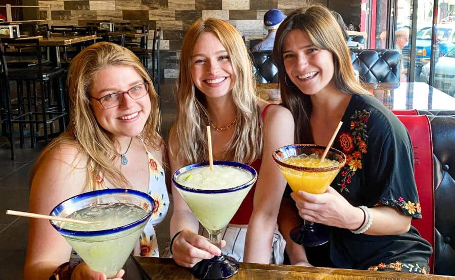 Three girls holding a glass of margarita each